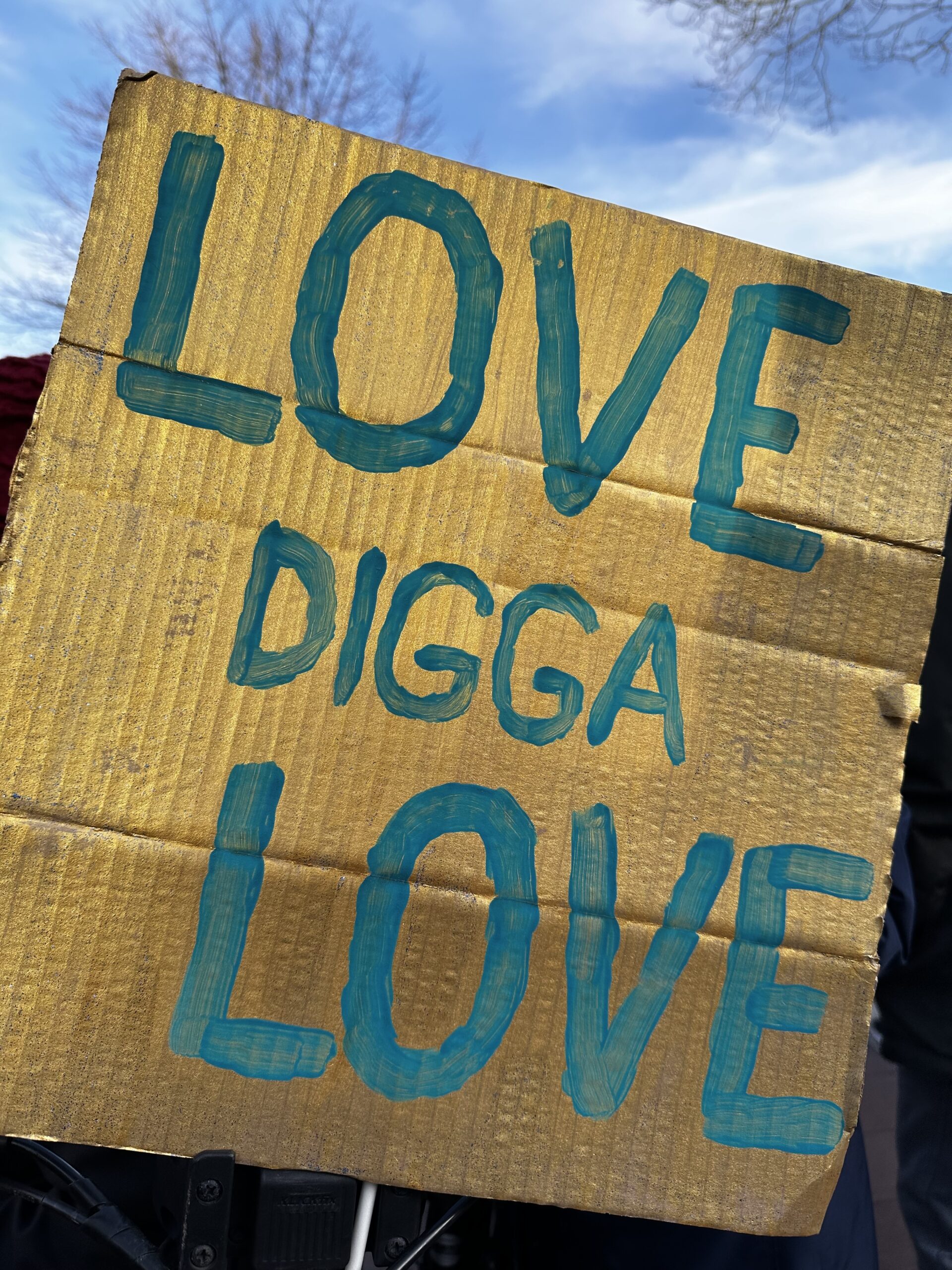 Ein goldenes Schild, auf dem in türkiser Schrift steht: Love digga love.