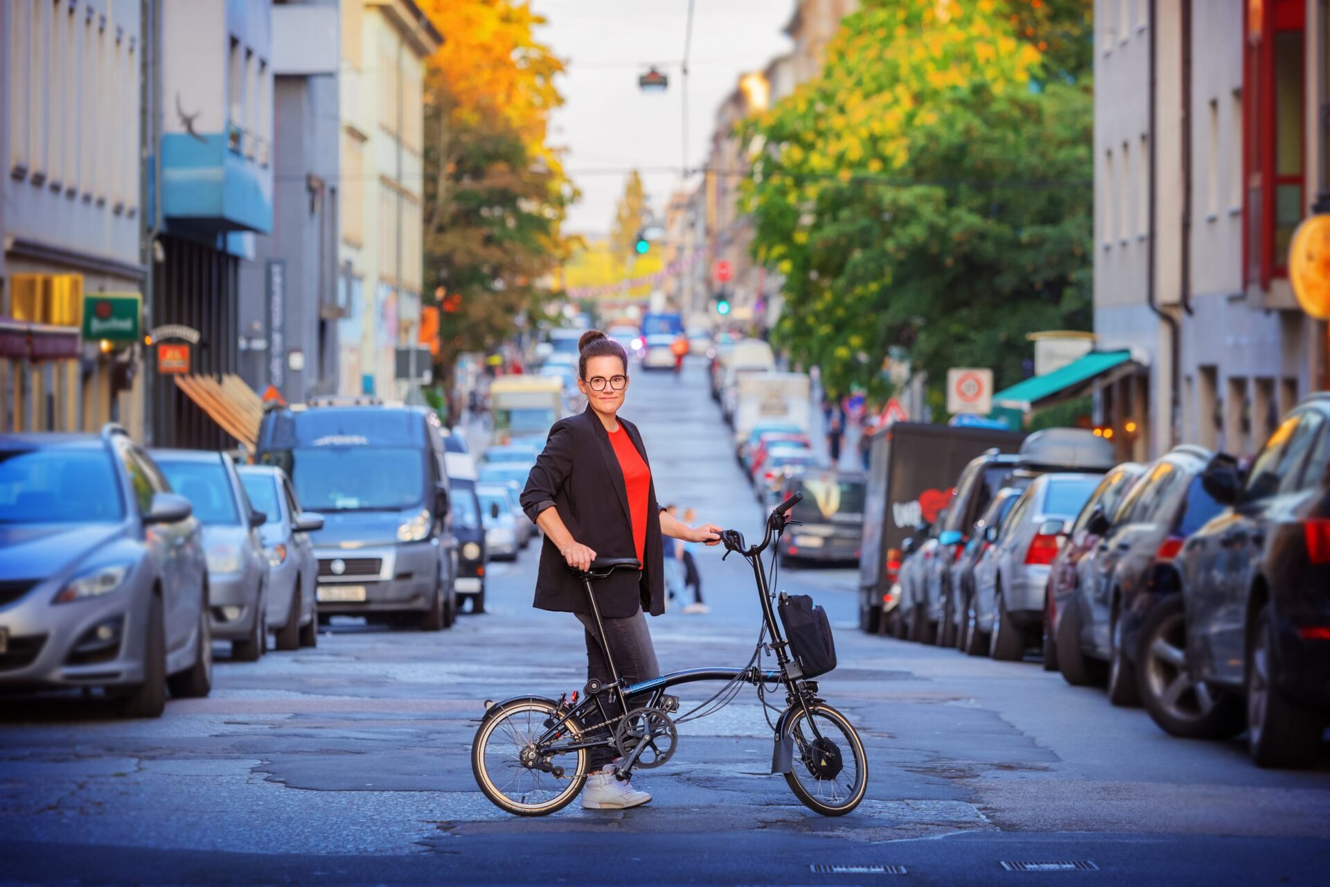 Eine Person mit einem Faltrad steht mitten auf der vollgeparkten Straße und schaut in die Kamera Foto: Amac Garbe